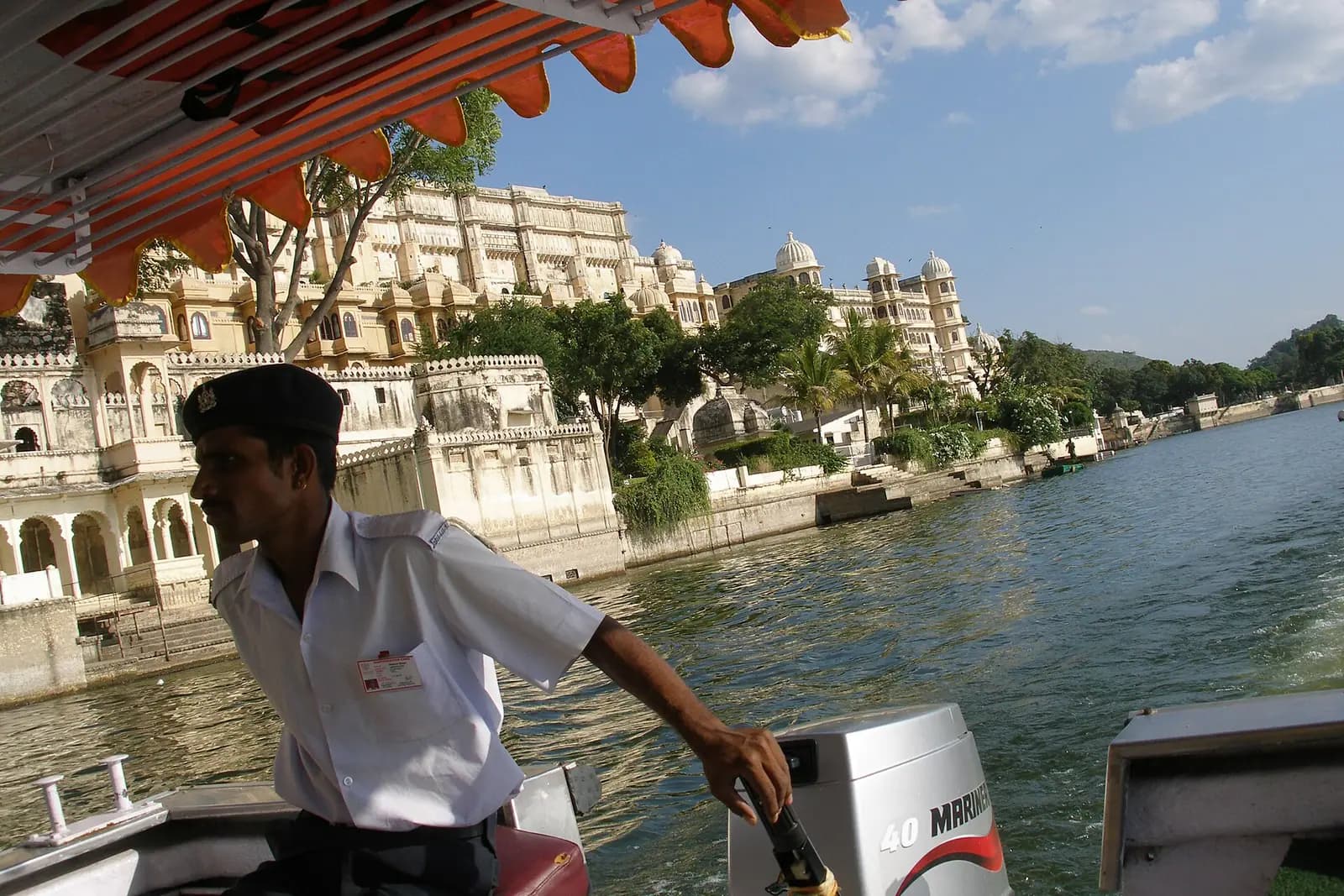 A boat crossing Lake Pichola below the palaces of Udaipur, Rajasthan