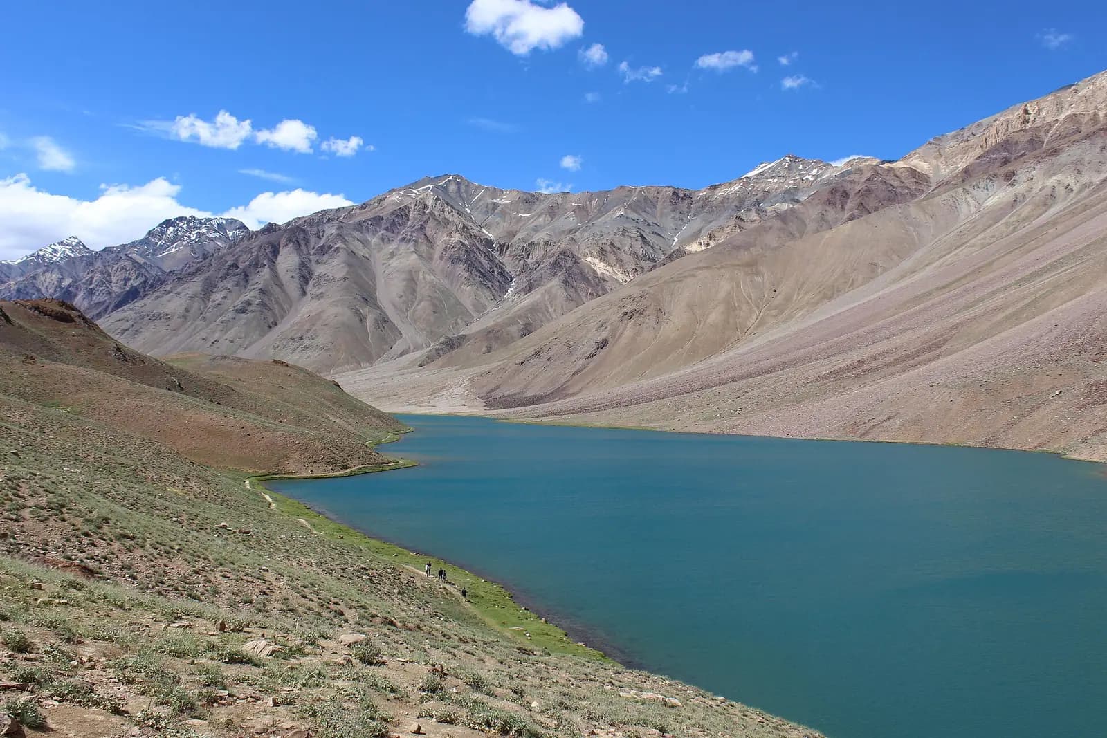 The turquoise water of Chandratal lake below bare mountain slopes, Spiti, Himachal Pradesh