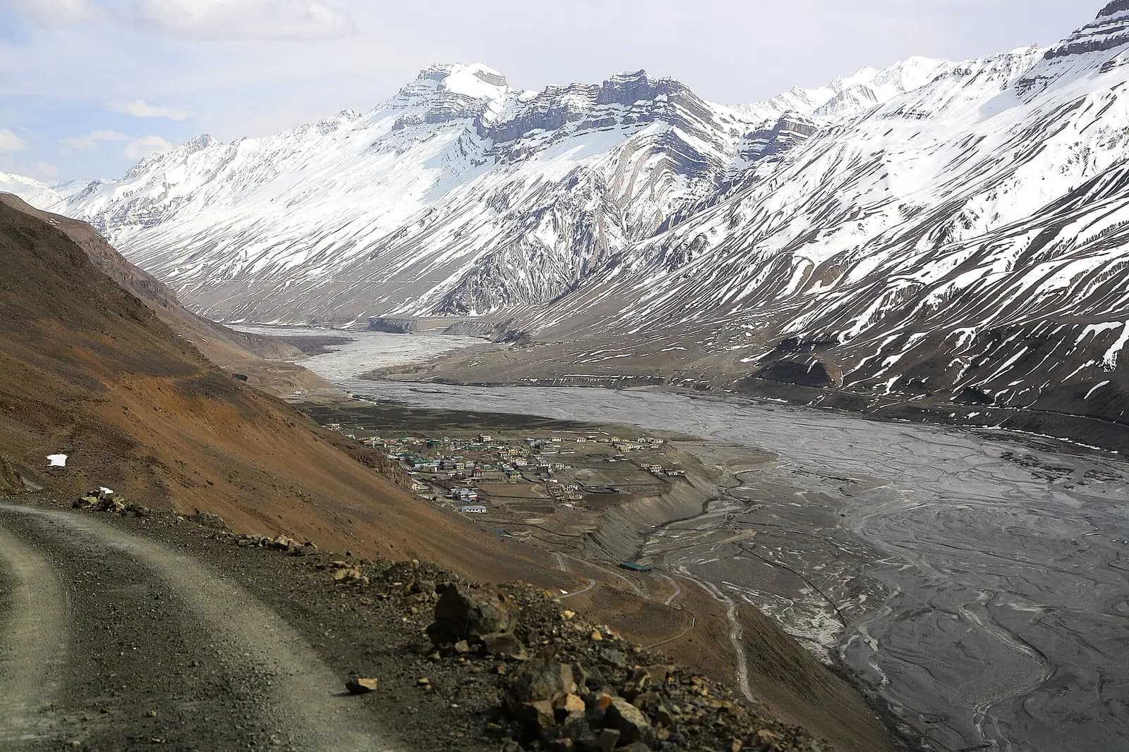 A gravel road descending into the snow-rimmed Spiti valley towards Kaza